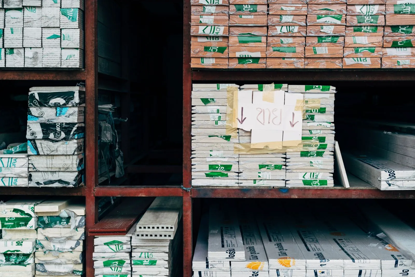 Steel pipes, timber, and construction materials stored in an organized industrial warehouse.